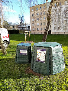 Deux composteurs de Limoges Métropole sont disposés dans un espace vert en pied d'immeuble.