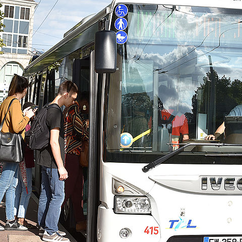 Des personnes montent dans un bus de Limoges Métropole qui est à l'arrêt.