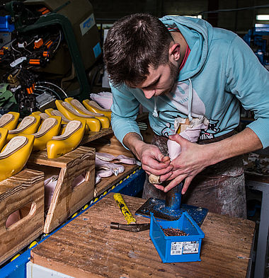 Un ouvrier de l'entreprise Danse Azur est dans son atelier et est en train de concevoir des chaussures de danse.