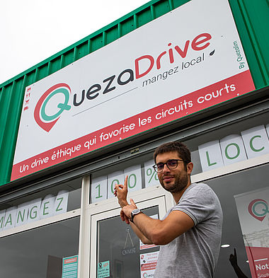 Le dirigeant de l'entreprise QuezaDrive pose devant le local de l'entreprise.