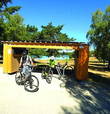 Deux personnes avec des vélos sortent leurs vélos d'une station-service autonome développée par e-BikePort.