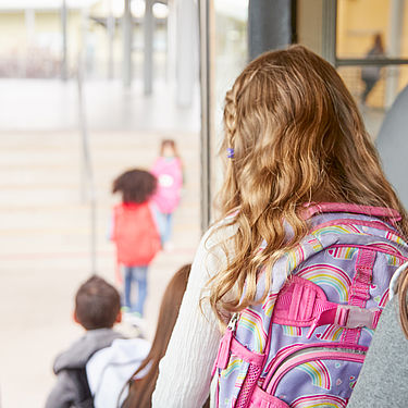 Des enfants sortent d'un bus scolaire, cartables sur le dos