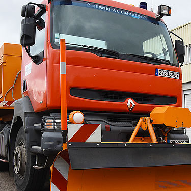 Un chasse-neige de Limoges Métropole est stationné sur le parking d'un entrepôt.