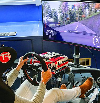 Une personne est installée dans un simulateur et participe à une course virtuelle de sport automobile.