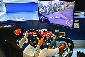 Une personne est installée dans un simulateur et participe à une course virtuelle de sport automobile.